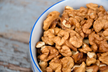Walnuts. Walnut kernels. Clean organic walnuts. Nuts in the cup on vintage blue wooden background. Walnut tree fresh fall harvest.