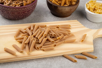 Assorted whole wheat pasta on bowls over wooden table