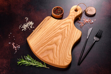 Cutting board with salt, spices and herbs on a dark concrete background