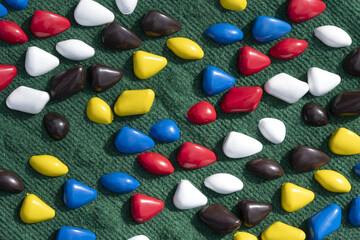 texture with multi-colored stones. objects of different colors on a green background. multicolored pebbles