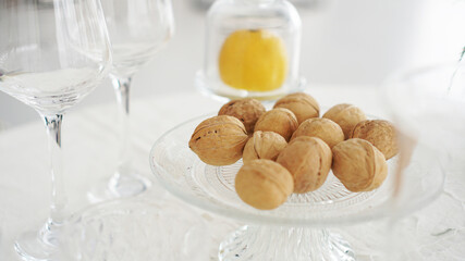 Empty wine glasses and walnuts on a glass plate on blurred background of modern interior