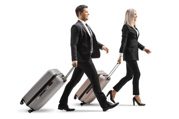 Full length profile shot of a young businessman and businesswoman walking and pulling suitcases