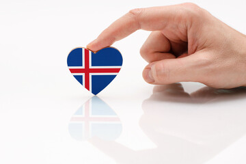 Love and respect Iceland. A man's hand holds a heart in the shape of the Iceland flag on a white...