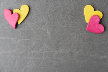 Valentine’s Day background with decorative pink and yellow hearts on stone surface
