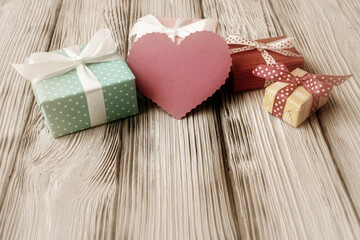 Gift boxes and heart shaped blank card on aged wooden background