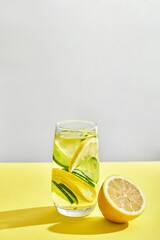 glass of cool homemade lemonade on a yellow background with space for text