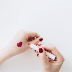 An image of a heart painted in lipstick on a woman's hand.On a white background.Top view.Love, friendship, and a declaration of love.Happy Valentine's Day.The minimal concept of celebration and love