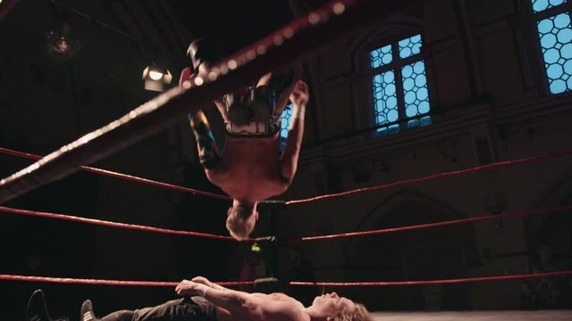 Pro wrestling match - wrestler backflip onto opponent in ring