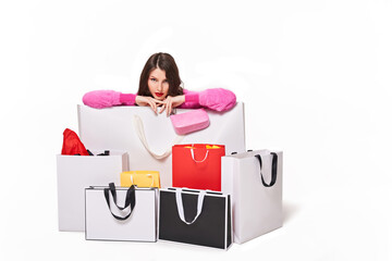 Woman sitting behind shopping bags on white background