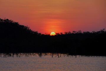 Naklejka premium Orange smoke filled sky at sundown over a ridge at Lake Bennett in the Northern Territory of Australia