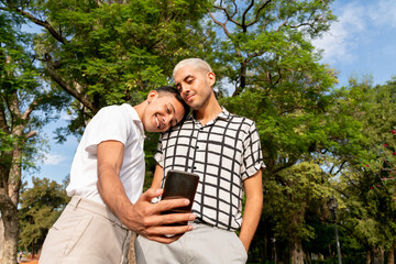 Young gay couple taking selfies a public park