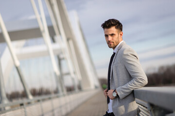 Portrait of a young businessman on the bridge. Yuppie outdoors