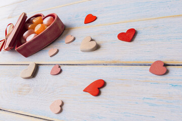 Candies in wooden heart shaped gift box and decorative hearts. Valentine ’s Day greeting