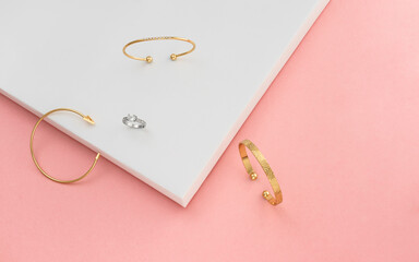 Top view of three bracelets and ring on pink and white background