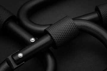 Black carabiners on a black background. Outdoors climbing equipment adventure stacked
