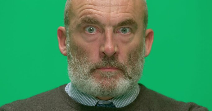 Studio, slow motion, a portrait of a seething mature man against a green screen, London, UK