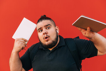 Portrait of a funny man with a beard and overweight with a notebook and a book in his hands on a...