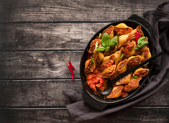 Conchiglioni stuffed with minced meat and baked in tomato sauce, close-up, top view. Copy Space