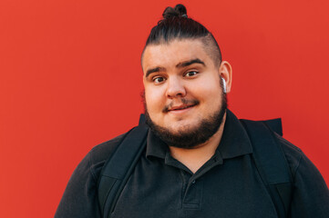 Close up portrait of funny overweight man on red background, looking at camera with happy face.