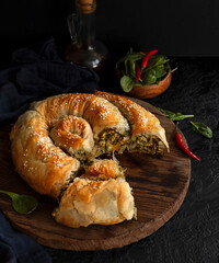 Traditional Greek pastries. Snail with cheese and spinach. Roll with filling on a wooden rustic table - 412682815