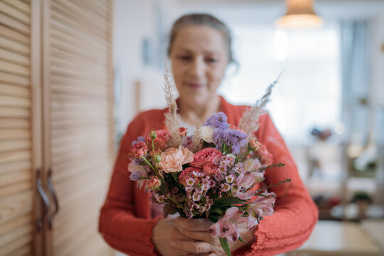 Portrait Of An Elderly Woman Holding Flowers.