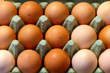 Large brown and light country eggs in a paper tray.