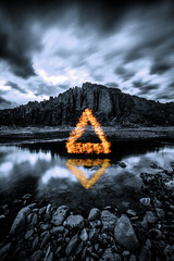 Long exposure, light painted fire triangle in the mountains, reflected on water