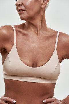 Slim middle aged woman in bra demonstrating fit body