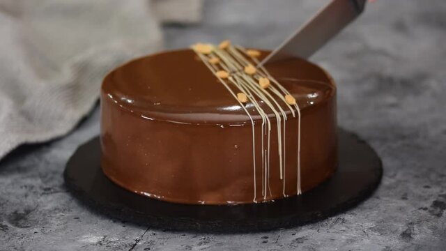 Cutting a chocolate caramel peanut mousse cake and mirror glaze.