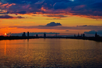 sunset. in the photo, the clouds are illuminated by the evening sun,in the foreground is a river, in the background is a city
