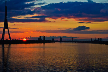 sunset. in the photo, the clouds are illuminated by the evening sun,in the foreground is a river, in the background is a city