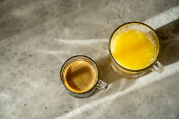 a cup of coffee with glass of orange juice on a table. sunny morning. Gray background. Top view