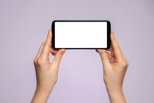 Smartphone horizontally with a blank screen in a woman's hand.