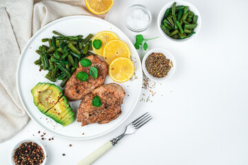 Delicious chicken breast with beans, avocado, spices and lemon on a white background. Top view, horizontal. The concept of healthy eating.