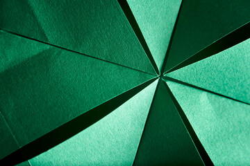 Abstract radial green background of textured paper folded using origami. Concept of geometry.