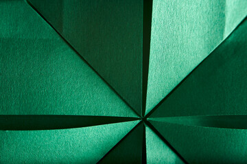 Abstract radial green background of textured paper folded using origami