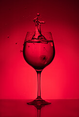 Splash of water in a glass on a red background. Unusual sculptures