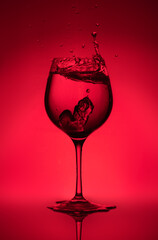 Splash of water in a glass on a red background. Unusual sculptures