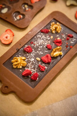 Handmade chocolate with fresh and dried fruits on light paper background in rustic style