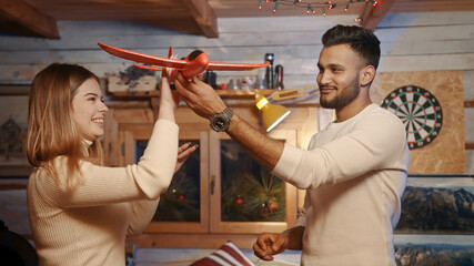 Fototapeta na wymiar Happy young couple playing with red airplane toy. Planning winter vacation. High quality photo