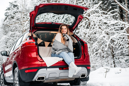 winter romance concept car travel in winter, in red car drinks hot tea from a thermos, picnic in a frosty winter forest, valentine