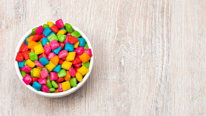 Colored chewing gum in the bowl - Wooden background