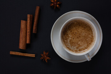 A mug of aromatic coffee with cinnamon sticks on a dark background. 