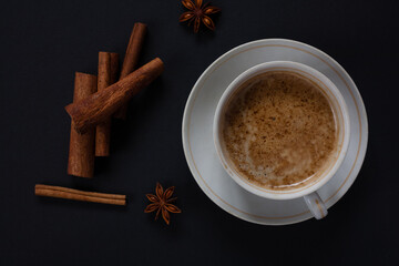 A mug of aromatic coffee with cinnamon sticks on a dark background. 