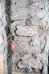 A close-up of a wall with stripped plaster and uncovered brickwork.