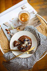 pancakes on a white plate with a cup of coffee and golden cutlery