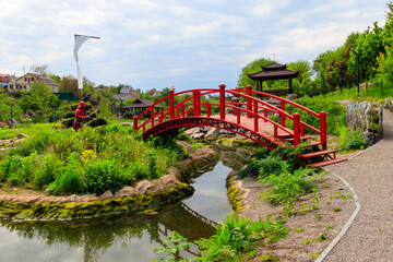 Red bridge and gazebo by a pond in Japanese garden