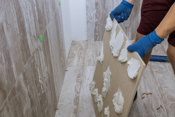 Tiler and plaster repair work laying tile, trowel in a man hand