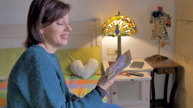 plano lateral de mujer senior hablando con familia con una tableta digital