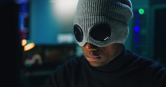 Black hacker in mask using computer